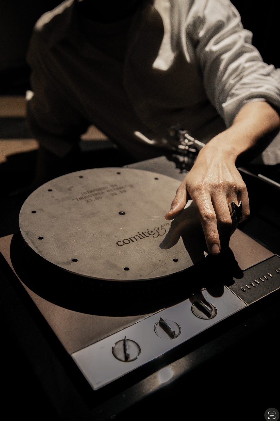 Mano ajustando un disco de metal grabado con Comité 357 sobre un tocadiscos vintage